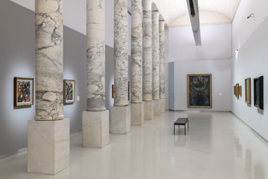Galleria espositiva monumentale con colonnato in marmo venato, pavimenti lucidi e quadri illuminati lungo le pareti.