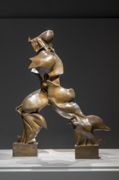 Scultura in bronzo dinamica e fluida che raffigura una figura umana in movimento, illuminata su uno sfondo scuro ed essenziale.